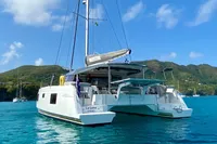 2022 Nautitech 40 Open catamaran anchored in clear blue water, scenic mountain backdrop.