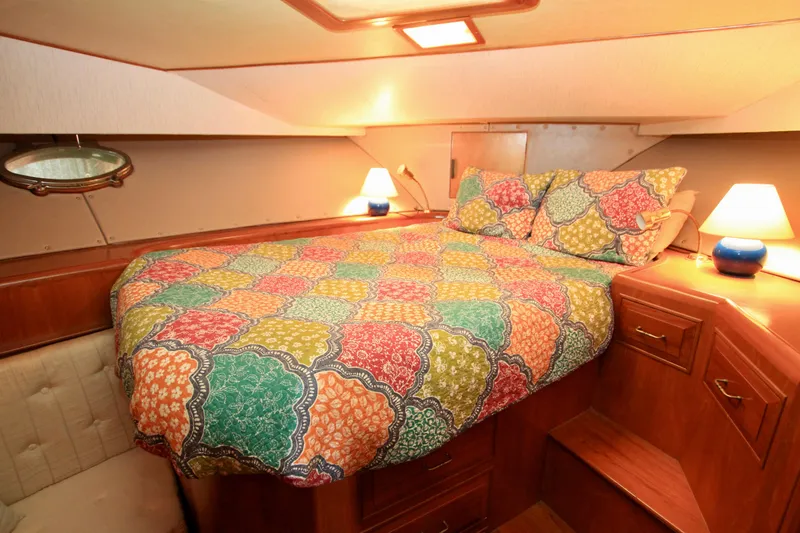 Sea Mistress Yacht Photos Pics Cozy bedroom in 1987 Ocean Alexander 42 yacht with colorful bedding and warm lighting.
