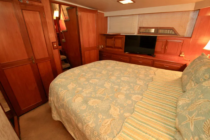 Sea Mistress Yacht Photos Pics Luxurious bedroom interior of 1987 Ocean Alexander 42 yacht with wood paneling and cozy bedding.