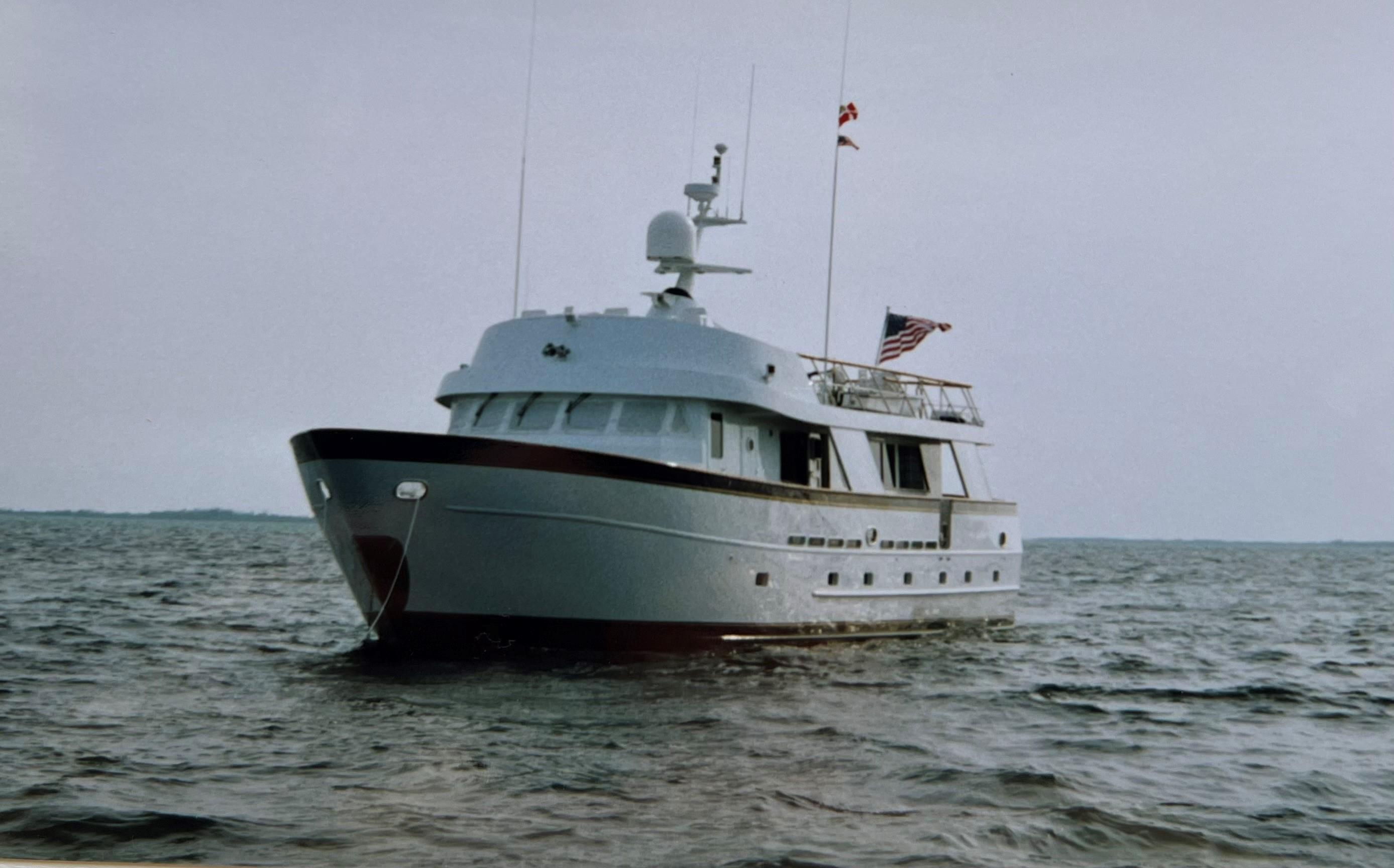 Custom 1988 steel motor yacht on open water, featuring sleek design and American flag.