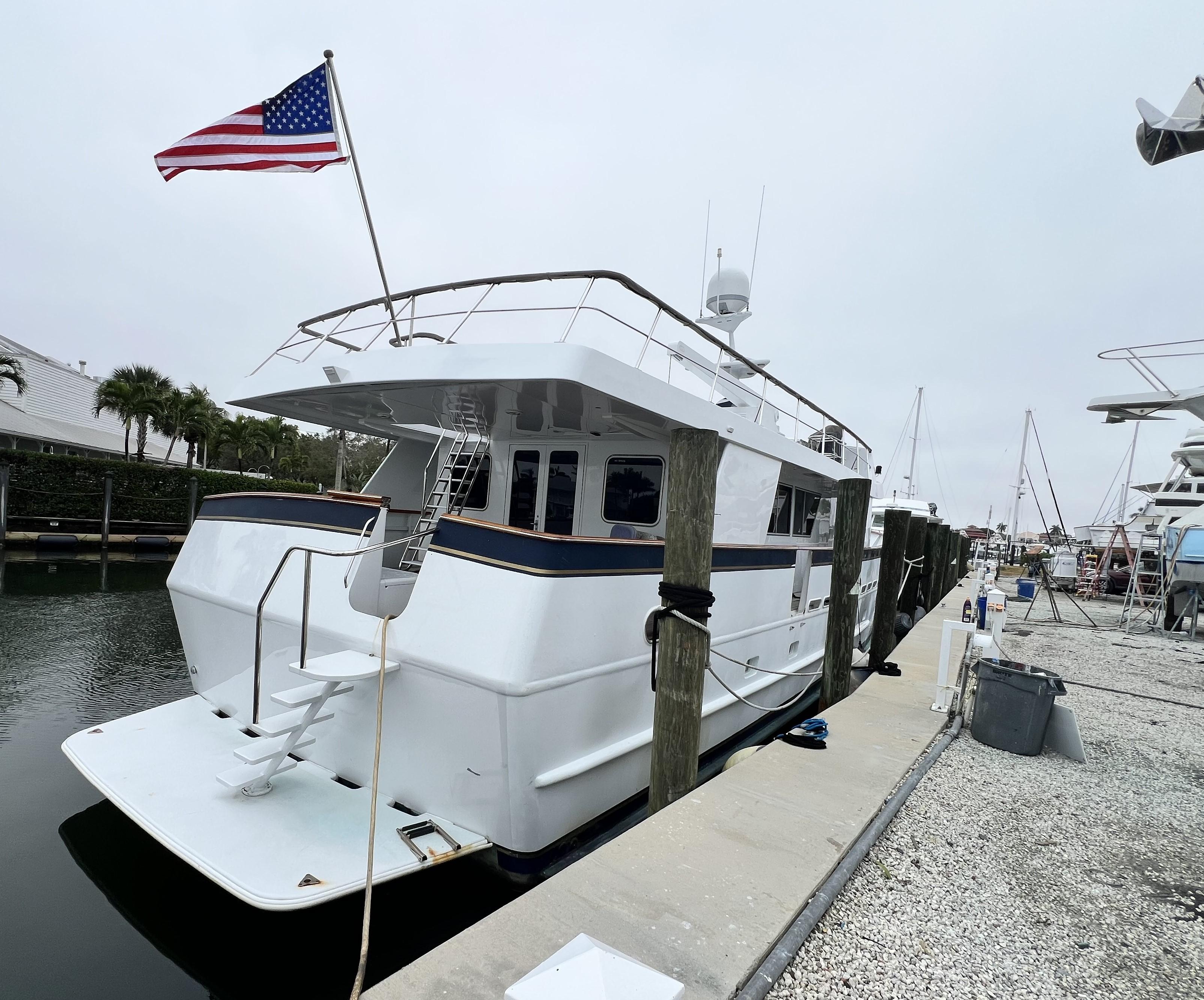 Custom 1988 steel motor yacht docked, displaying American flag, with sleek white design.