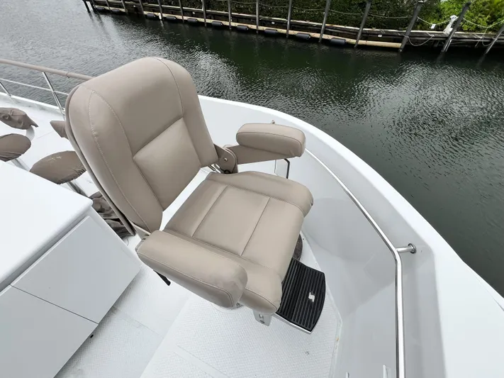 Ain't No Big Thing Yacht Photos Pics Luxurious beige captain's chair on 1988 Custom Steel Motor Yacht deck, overlooking serene waterway.