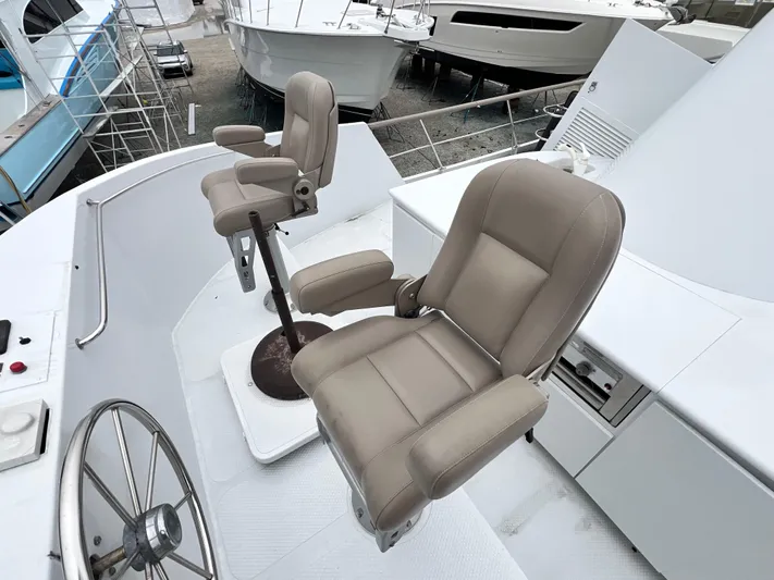 Ain't No Big Thing Yacht Photos Pics Captain's chairs on 1988 Custom Steel Motor Yacht deck, featuring steering wheel and control panel.