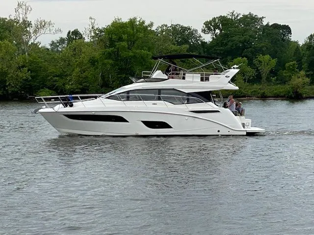  Yacht Photos Pics 2017 Sea Ray Fly 460 yacht cruising on a calm river with lush greenery.