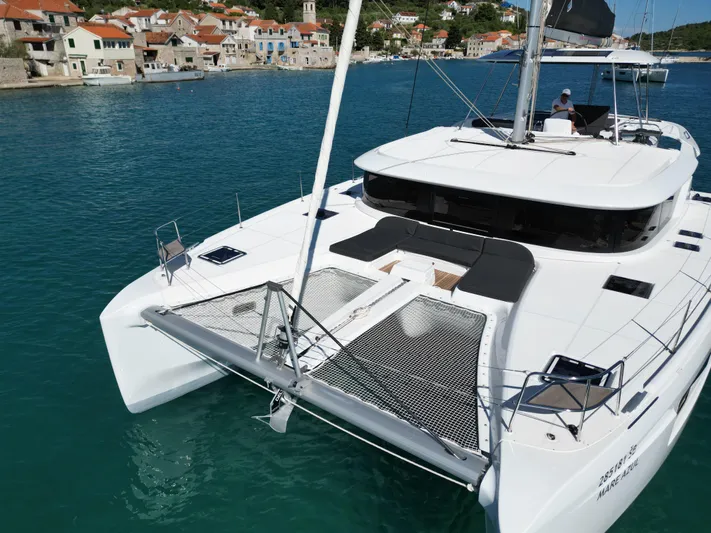 Mare Azul Yacht Photos Pics 2024 Lagoon 46 catamaran docked in a scenic harbor with coastal village backdrop.