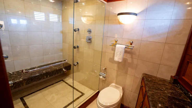  Yacht Photos Pics Luxurious bathroom in 1999 Burger 85 Deck house with glass shower and marble accents.