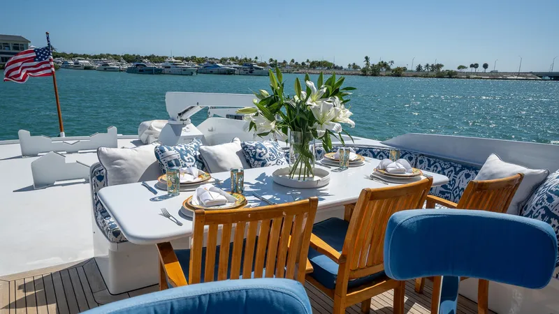  Yacht Photos Pics Luxurious dining setup on 1999 Burger 85 Deck house yacht, overlooking serene waters.