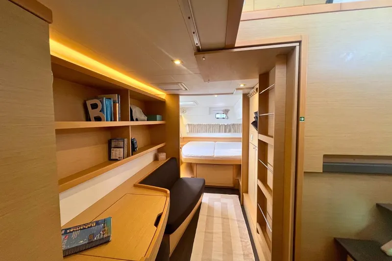 Twin Joy Yacht Photos Pics Interior of 2019 Lagoon 50 yacht, featuring cozy cabin with desk, shelves, and bed.