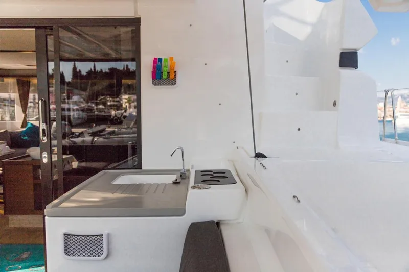 Twin Joy Yacht Photos Pics Outdoor kitchen area on a 2019 Lagoon 50 catamaran, featuring a sink and stove.