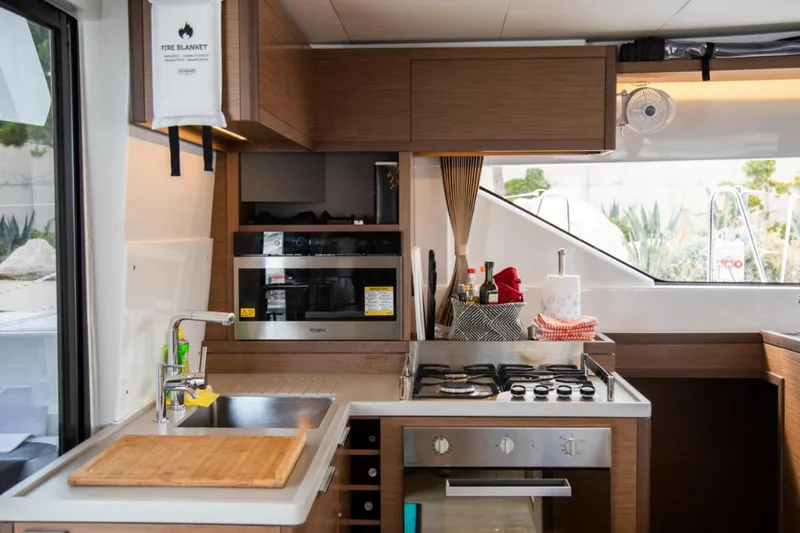 Twin Joy Yacht Photos Pics Modern kitchen in 2019 Lagoon 50 yacht with stove, sink, and wooden cabinetry.