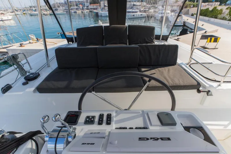 Twin Joy Yacht Photos Pics Helm station of 2019 Lagoon 50 catamaran with cushioned seating and marina view.