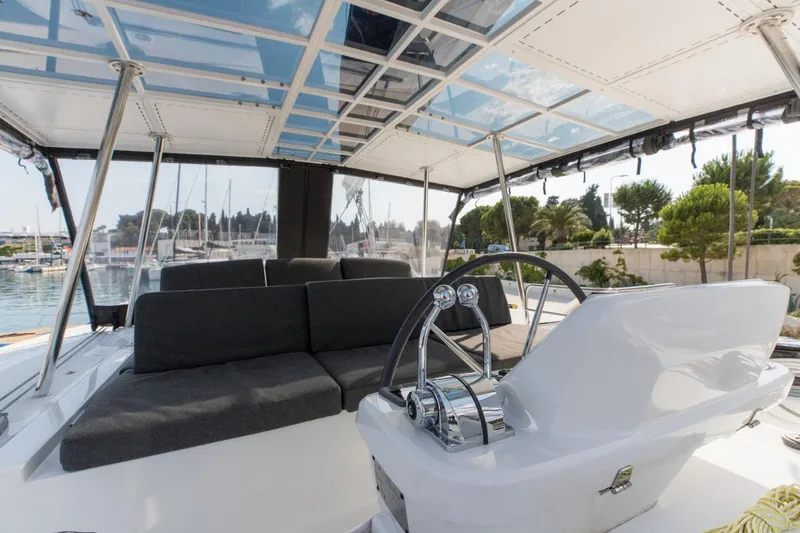 Twin Joy Yacht Photos Pics 2019 Lagoon 50 yacht cockpit with modern seating and steering, docked at marina.