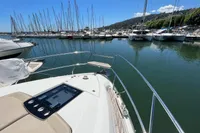 Fairline Targa 48 Open 2020 yacht docked in a marina with sailboats and clear blue sky.