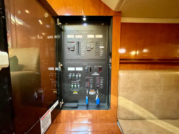 Deja Blue Yacht Photos Pics Electrical panel inside 2005 Sea Ray 390 Sundancer yacht, featuring wood cabinetry and seating.