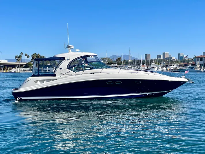 Deja Blue Yacht Photos Pics 2005 Sea Ray 390 Sundancer yacht cruising in a marina with city skyline backdrop.