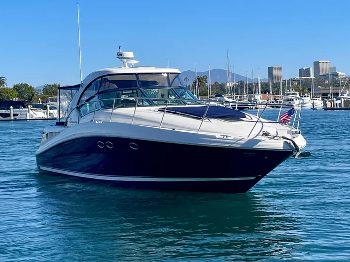 Deja Blue Yacht Photos Pics 2005 Sea Ray 390 Sundancer yacht cruising in a marina with cityscape background.