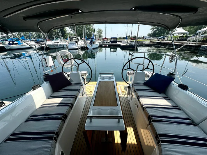  Yacht Photos Pics 2023 Beneteau Oceanis 34.1 yacht cockpit with striped seating, dual steering wheels, and marina view.