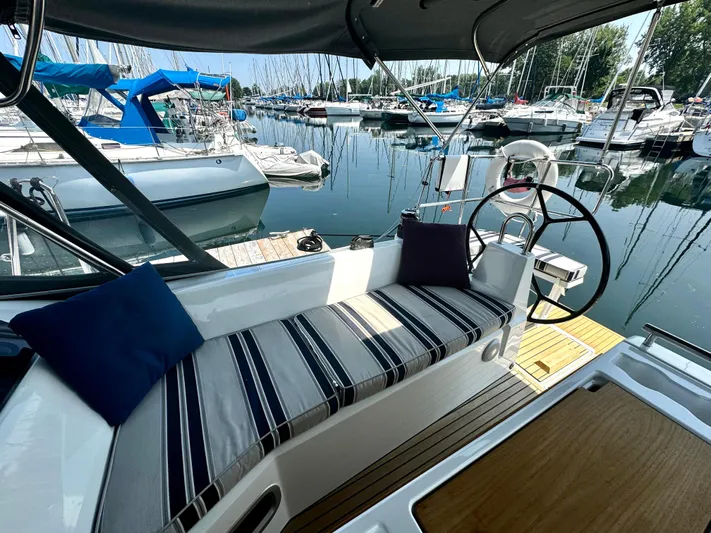  Yacht Photos Pics 2023 Beneteau Oceanis 34.1 yacht cockpit with striped seating, docked in a marina.