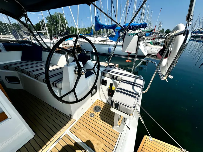  Yacht Photos Pics 2023 Beneteau Oceanis 34.1 sailboat cockpit with striped cushions and steering wheel.