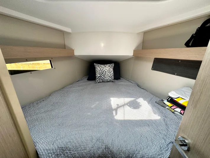  Yacht Photos Pics Cozy cabin interior of 2023 Beneteau Oceanis 34.1 with striped bedding and decorative pillow.