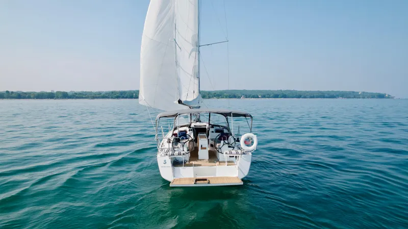  Yacht Photos Pics 2023 Beneteau Oceanis 34.1 sailing on calm waters, rear view.