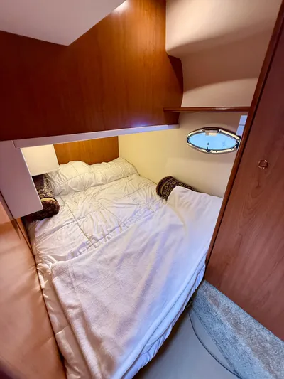  Yacht Photos Pics Cozy cabin bedroom in 2008 Silverton 33 Convertible yacht with wood paneling and porthole window.