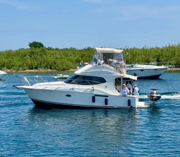  Yacht Photos Pics 2008 Silverton 33 Convertible yacht cruising on a sunny day near lush greenery.