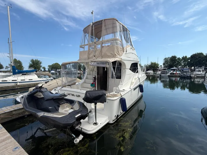  Yacht Photos Pics 2008 Silverton 33 Convertible yacht docked with jet ski, under clear blue sky.