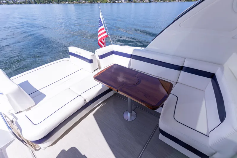  Yacht Photos Pics 2011 Sea Ray 450 Sundancer yacht deck with seating and table, American flag, on calm water.