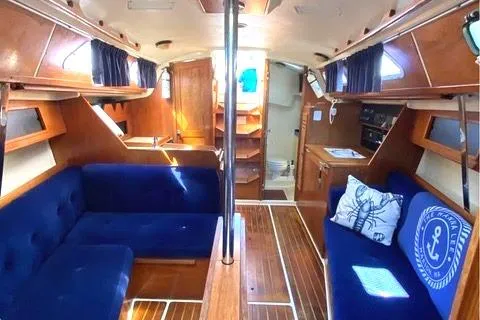 Interior of a 1986 Pearson 33-2 sailboat with blue seating and wooden finishes.