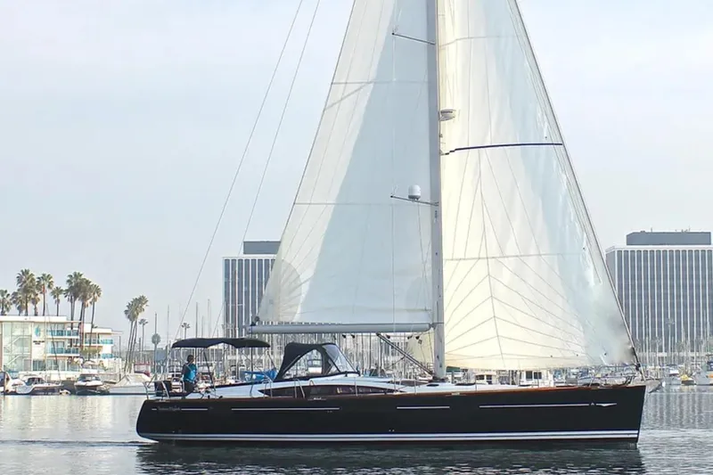 Tenacity Yacht Photos Pics 2011 Jeanneau 57 sailboat cruising in a marina with palm trees and buildings.
