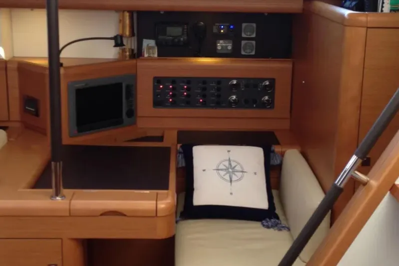 Tenacity Yacht Photos Pics Interior of 2011 Jeanneau 57 yacht with navigation equipment and compass-themed cushion.