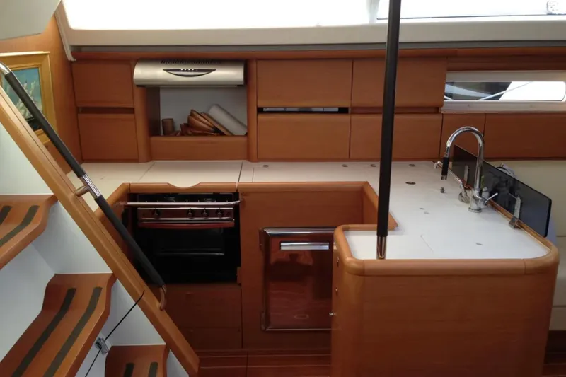 Tenacity Yacht Photos Pics Interior of 2011 Jeanneau 57 yacht kitchen with wooden cabinetry and modern appliances.