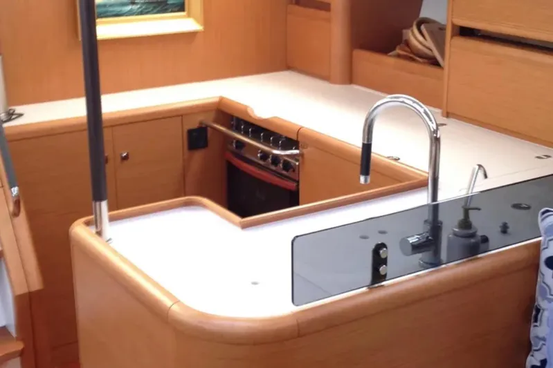 Tenacity Yacht Photos Pics Interior of 2011 Jeanneau 57 yacht kitchen with modern fixtures and wood cabinetry.