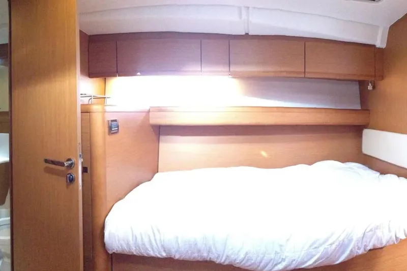 Tenacity Yacht Photos Pics Interior cabin of a 2011 Jeanneau 57 yacht with wooden finish and cozy bed.