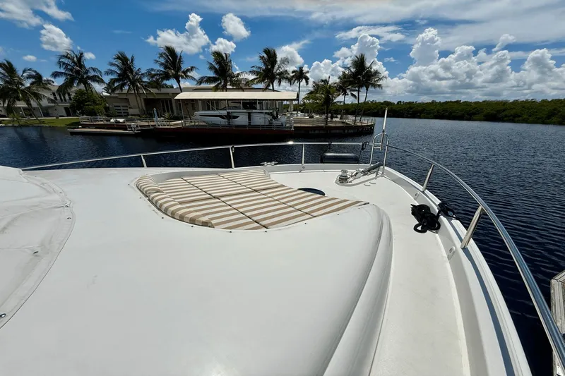 Marsha Sea Yacht Photos Pics 2005 Lazzara 68 Flybridge yacht deck with sunbed, docked near palm trees and calm water.