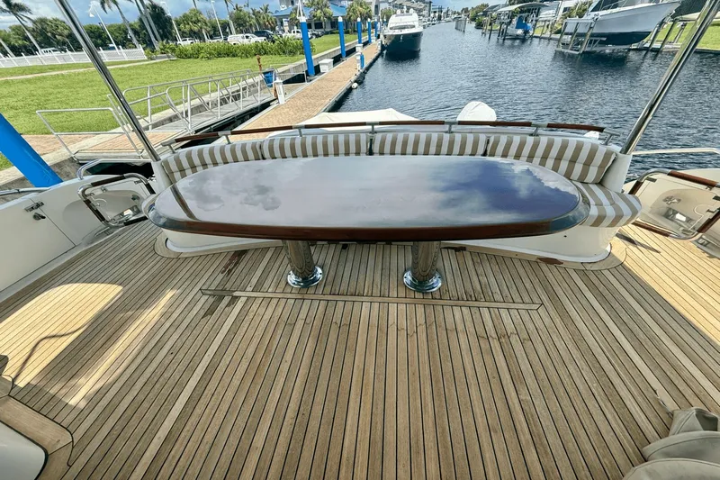 Marsha Sea Yacht Photos Pics 2005 Lazzara 68 Flybridge yacht deck with elegant wooden table and striped seating.