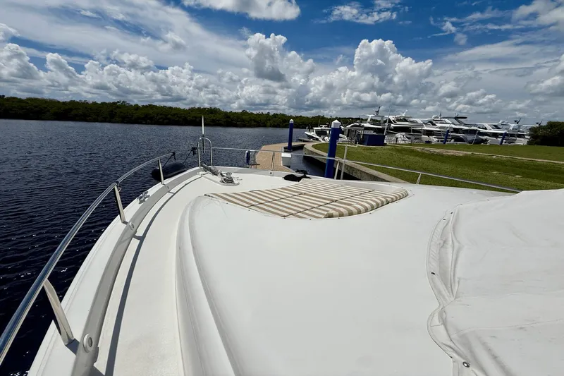Marsha Sea Yacht Photos Pics 2005 Lazzara 68 Flybridge yacht docked by a serene waterfront under a cloudy sky.