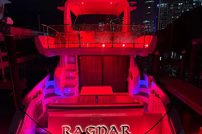  Yacht Photos Pics Red-lit Azimut Fly 53 yacht, 2013 model, docked at night with city skyline backdrop.