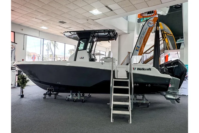  Yacht Photos Pics 2024 Wellcraft 263 Fisherman boat displayed indoors with ladder and Mercury engine.