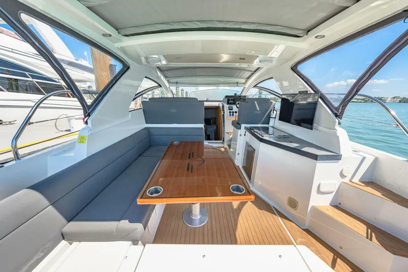  Yacht Photos Pics 2019 Sealine S330V yacht interior with seating, table, and kitchenette, overlooking the water.