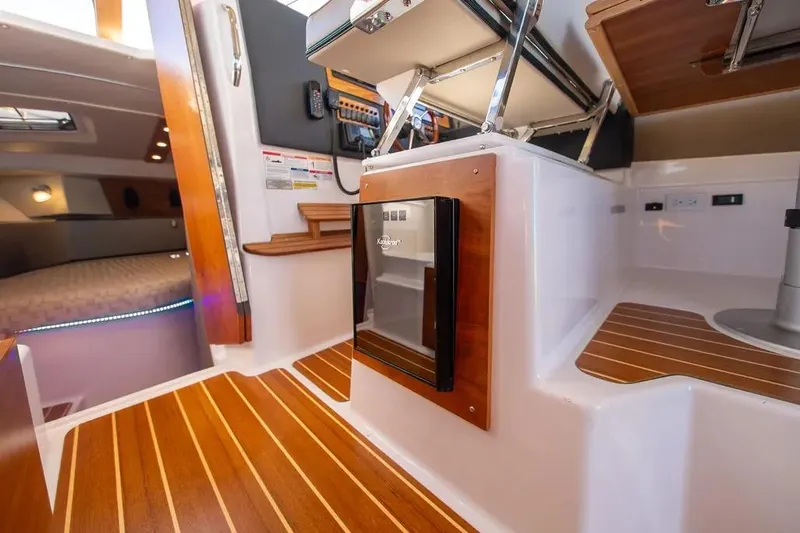  Yacht Photos Pics Interior of 2023 Cutwater C-32 Coupe boat with wood flooring and compact fridge.