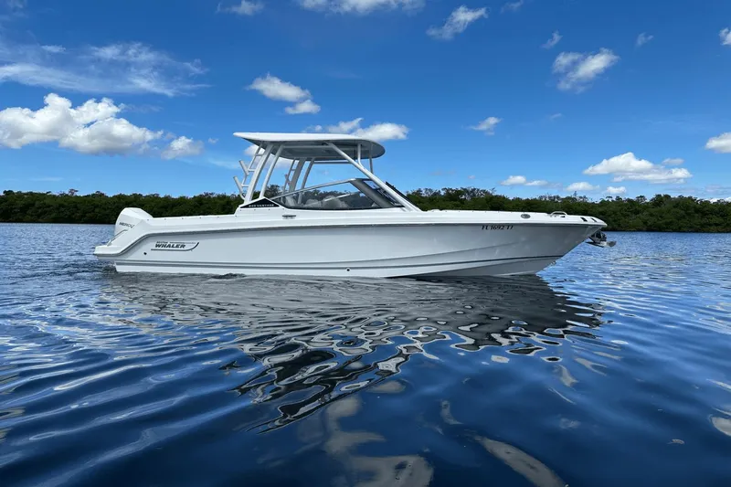  Yacht Photos Pics 2023 Boston Whaler 240 Vantage boat on calm water under a clear blue sky.