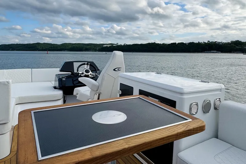  Yacht Photos Pics 2025 Cobrey 50 FLY yacht interior with helm, seating, and table on a scenic waterway.