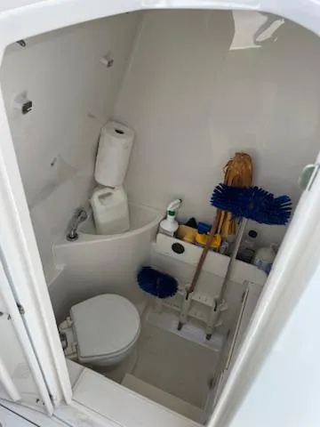  Yacht Photos Pics Compact boat bathroom with cleaning supplies, toilet, and storage on a 2006 Jupiter 31 Center Console.