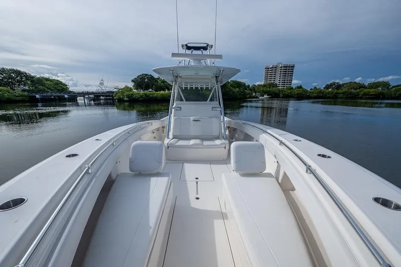  Yacht Photos Pics 2016 Invincible 39 Open Fisherman boat on calm water, surrounded by greenery and buildings.