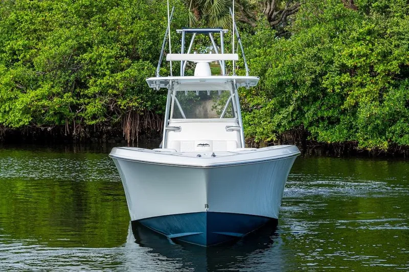  Yacht Photos Pics 2016 Invincible 39 Open Fisherman boat on calm water, surrounded by lush greenery.