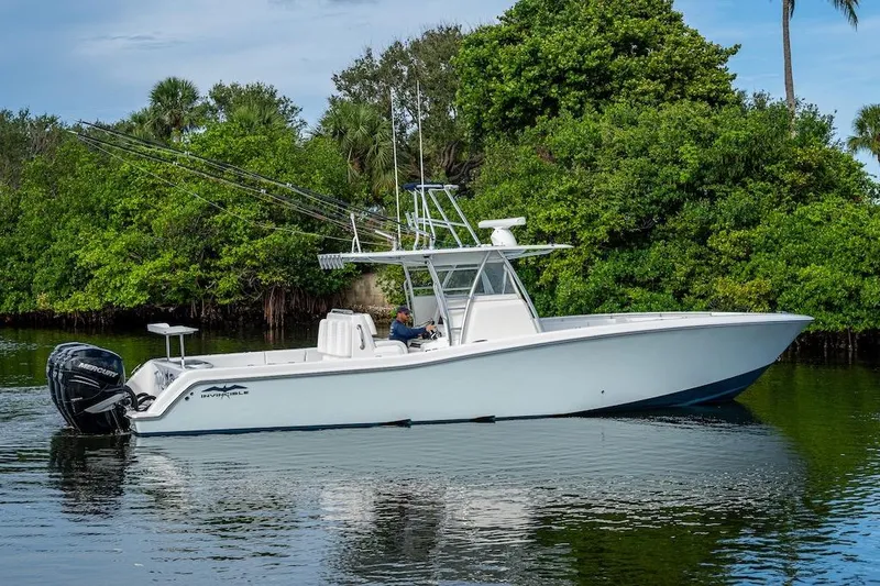  Yacht Photos Pics 2016 Invincible 39 Open Fisherman boat on calm water, surrounded by lush greenery.