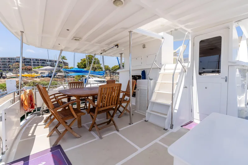 Si Como No Yacht Photos Pics Outdoor deck of 2009 DeFever 45 Motoryacht with wooden dining set and stairs.