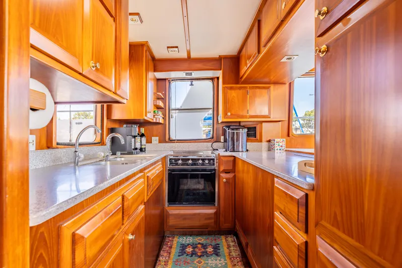 Si Como No Yacht Photos Pics Luxurious 2009 DeFever 45 Motoryacht kitchen with wooden cabinetry and modern appliances.